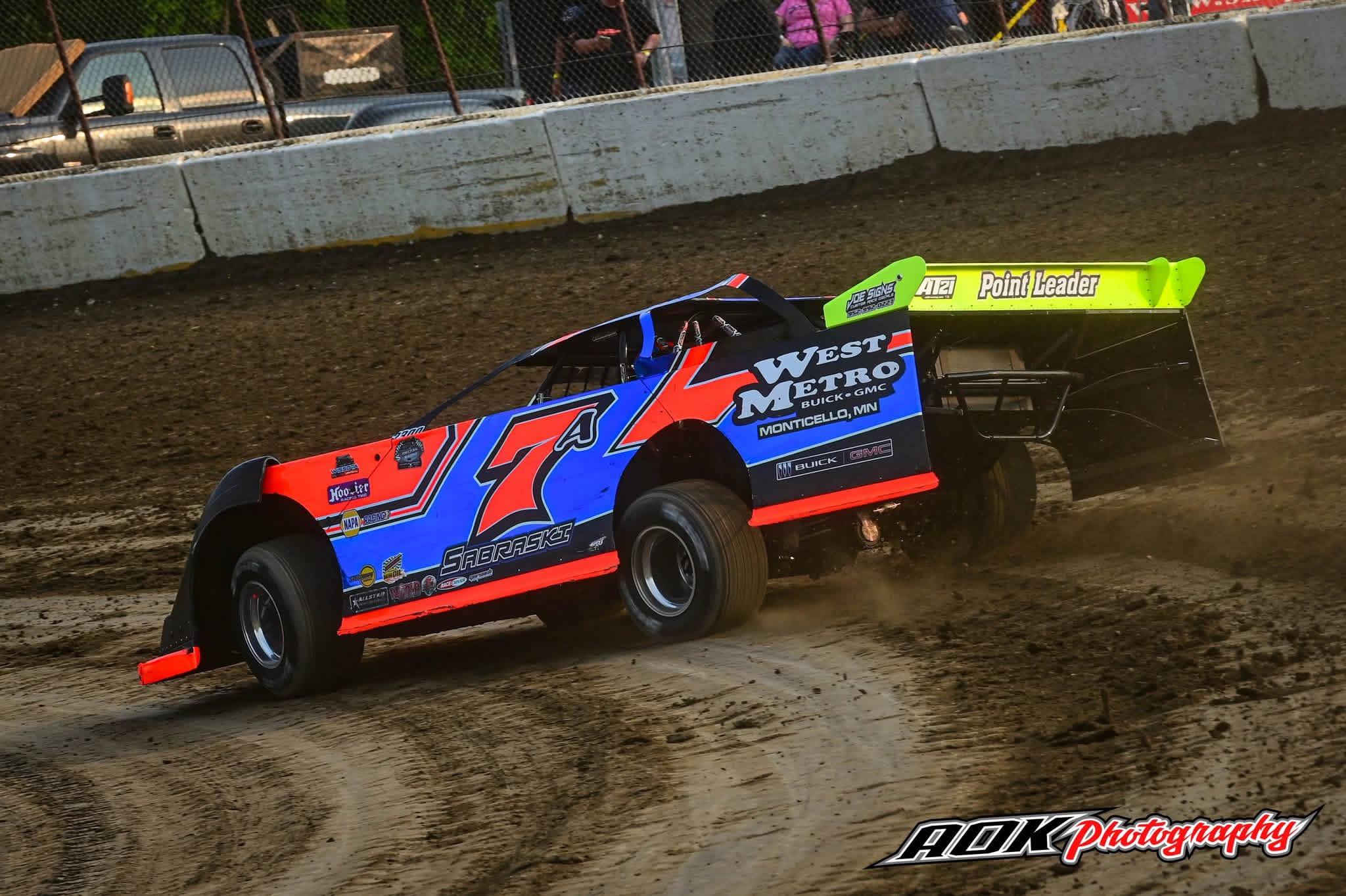 Colorful modified race car speeding on a dirt track.