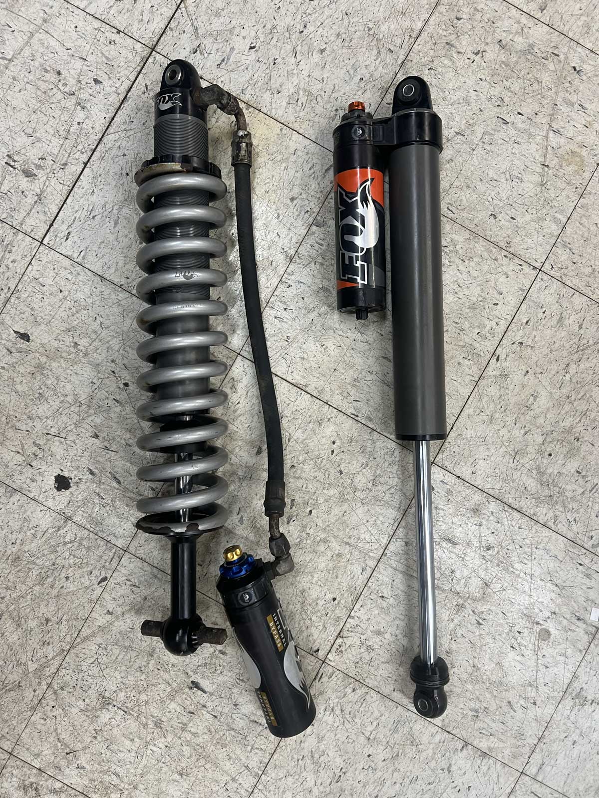 Two Fox motorcycle suspension shocks on workshop floor