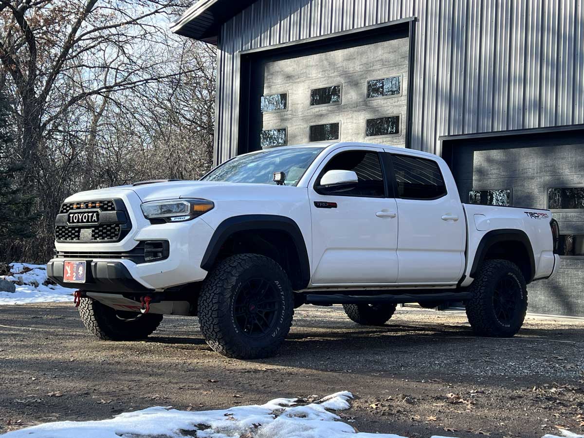White Toyota Tacoma pickup parked outside a metal garage