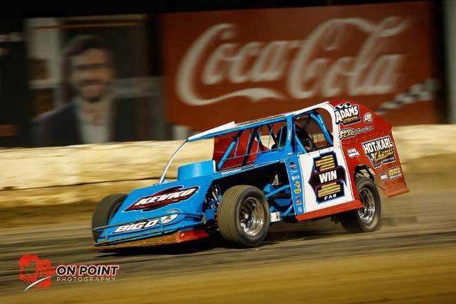 Blue and red modified race car speeding on dirt track
