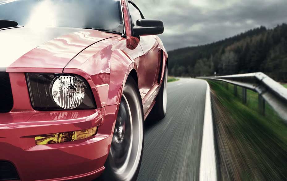 Red sports car driving fast on a winding mountain road