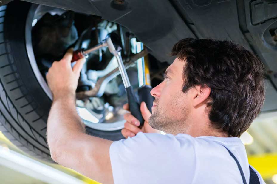 Mechanic repairing a car wheel suspension with tools