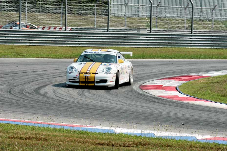 White race car with yellow stripes cornering on track